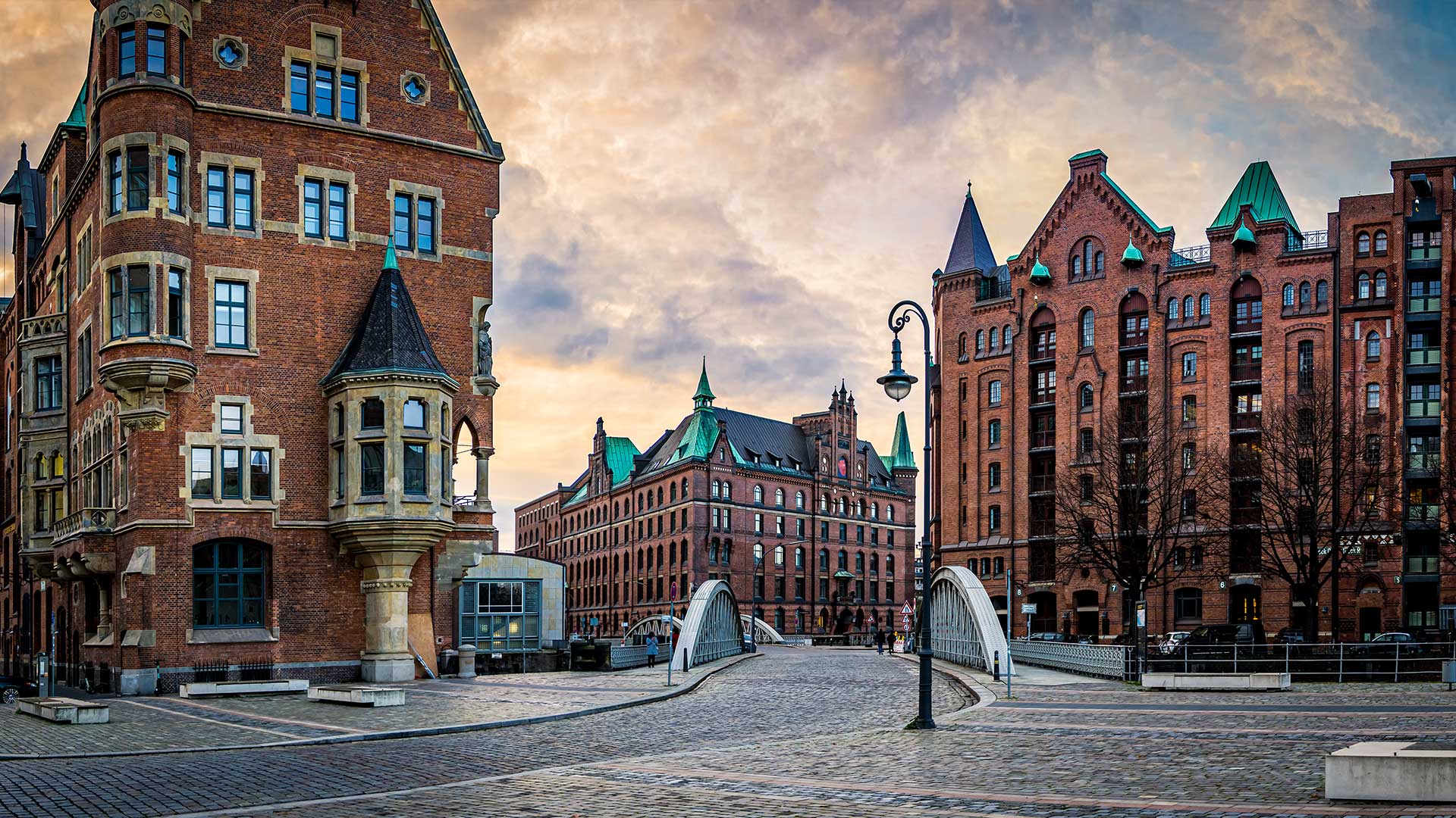 Historic brick buildings and a bridge at dusk in a cityscape.